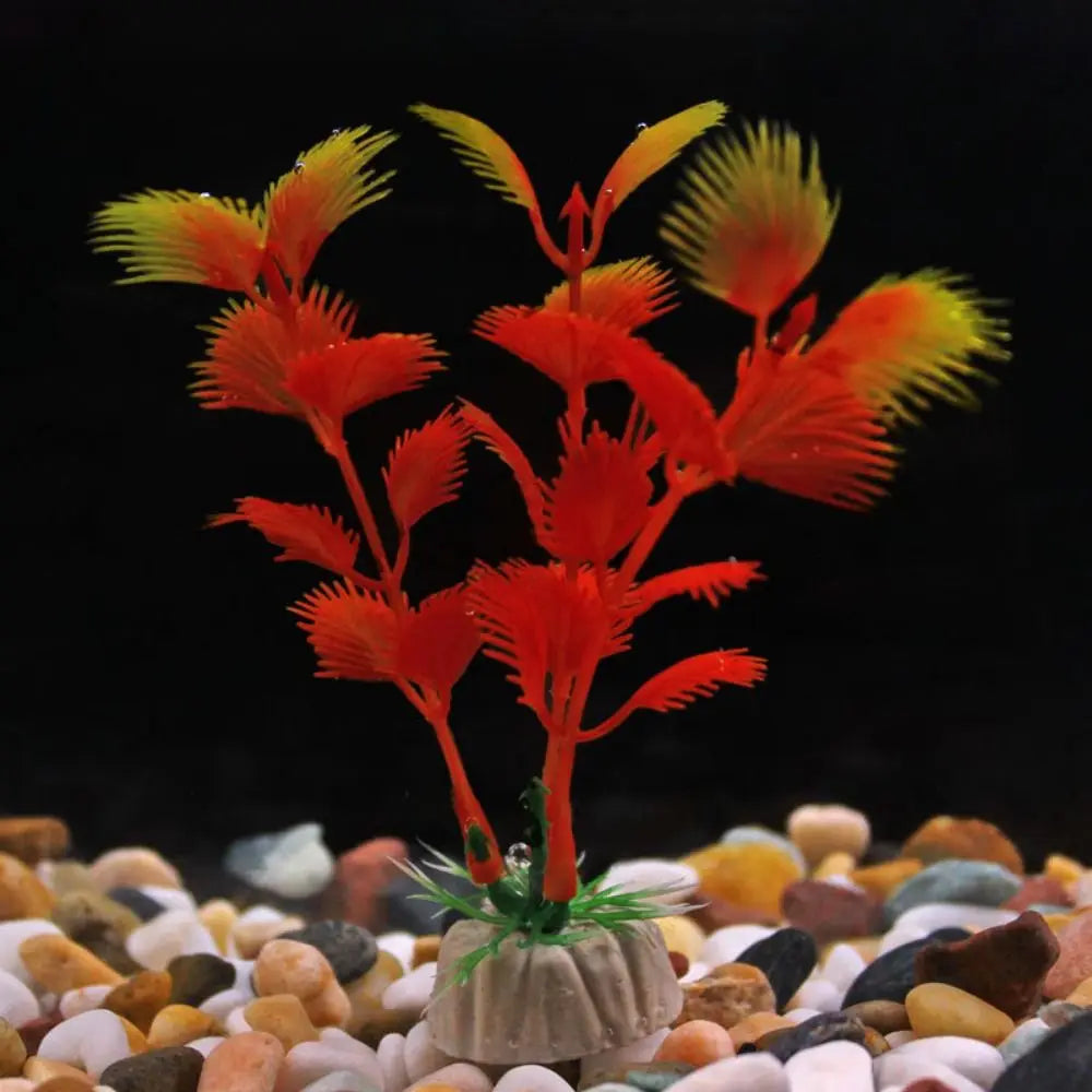 Artificial aquarium plant with orange and yellow feathered leaves on a weighted base, set against a black background.