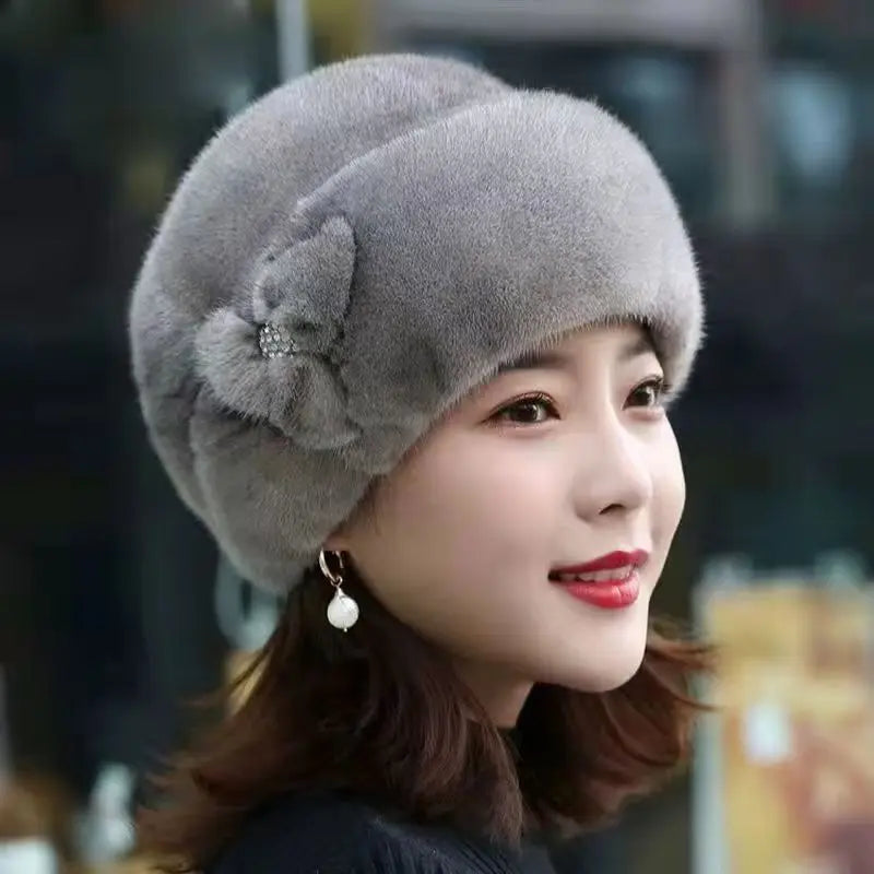 Elegant grey faux fur winter hat featuring a decorative side bow with a crystal embellishment.