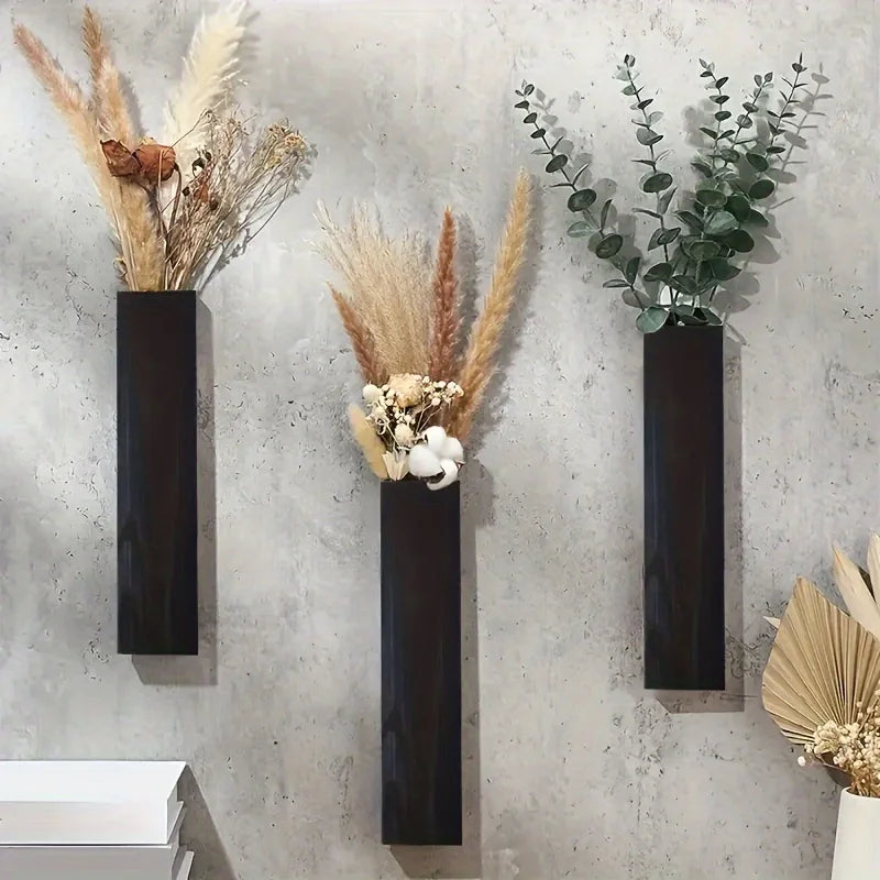 Three dark wooden rectangular wall-mounted vases, each filled with dried grasses and green eucalyptus stems.