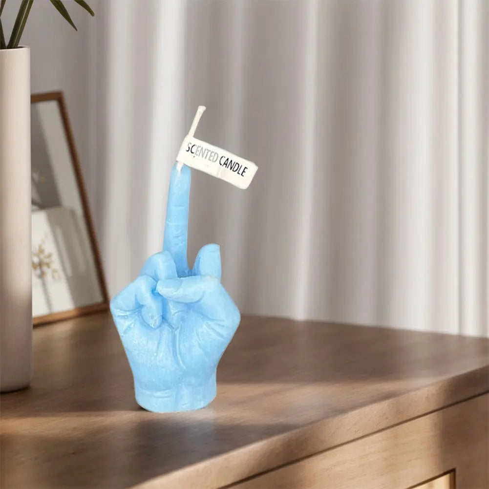 Light blue scented wax candle shaped like a hand giving a middle finger gesture, standing on a wooden surface.