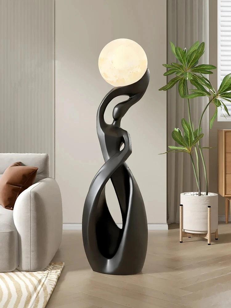 Elegant black abstract floor statue featuring a glowing, moon-like sphere, standing in a contemporary living room.