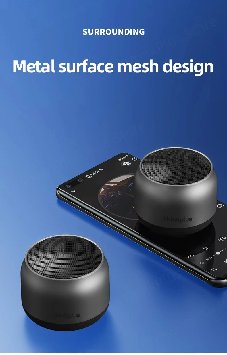 Two sleek, grey portable circular wireless speakers with metal mesh tops, one resting on a smartphone.