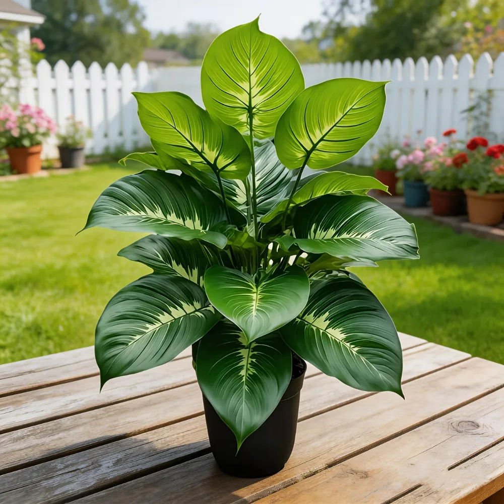 Artificial potted plant with vibrant, variegated green leaves featuring pale central veins, sitting on a wooden table.