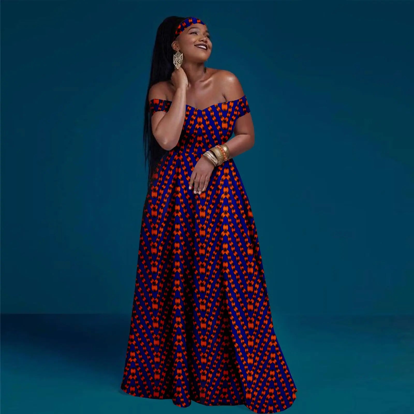 Model wearing an off-the-shoulder, floor-length maxi dress in blue and orange patterned fabric with a matching headband.