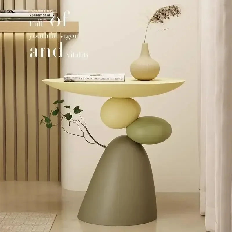 Minimalist cream and sage-green side table with a sculptural, stacked stone-like base and smooth, rounded tabletop.