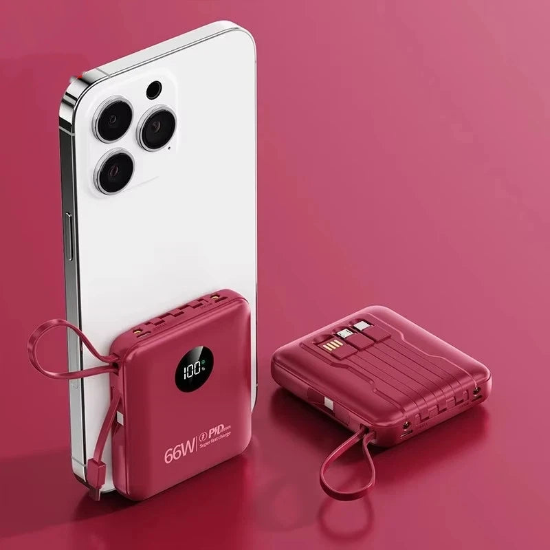 Red portable power bank with digital display, integrated cables and built-in carry loop, shown charging a smartphone.