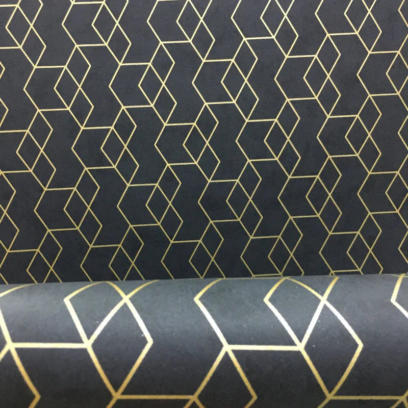 Modern wallpaper roll with a charcoal grey background and a repeating gold geometric cube pattern.