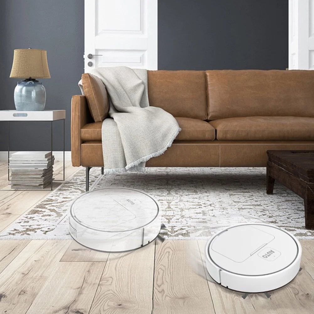 Two robotic vacuums clean the wood floor of a living room with a brown leather sofa.