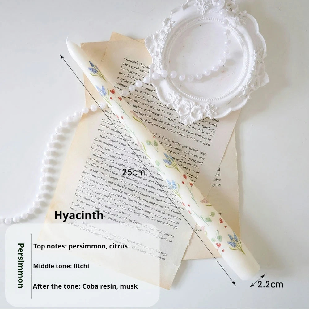 White tapered candle with delicate hyacinth floral print, 25cm tall, styled with vintage paper and pearl beads.