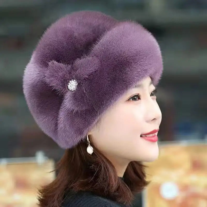 A woman wearing an elegant, purple faux fur winter hat featuring a decorative side bow with a sparkling crystal detail.
