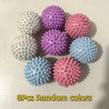 Eight colourful, spiky massage balls in various pastel shades arranged on a white surface.