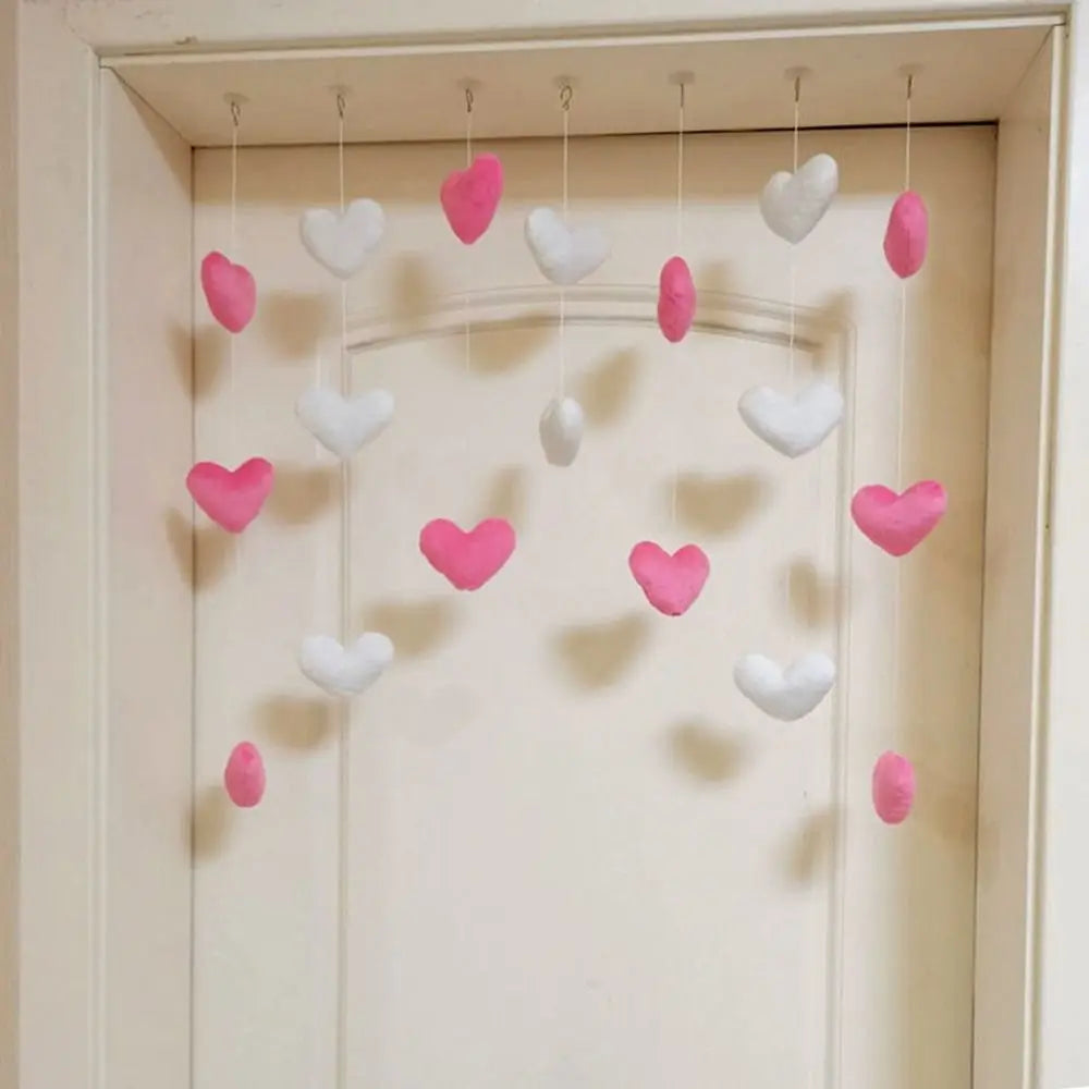 Hanging bedroom decoration with felt white and pink hearts on individual strings suspended in a doorway.