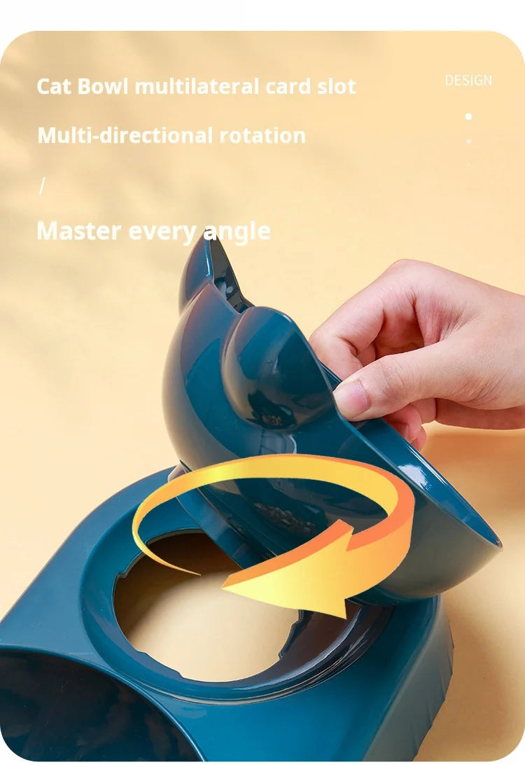 Hand adjusting the angle of a dark teal, rotating cat feeding bowl set against a soft yellow background.