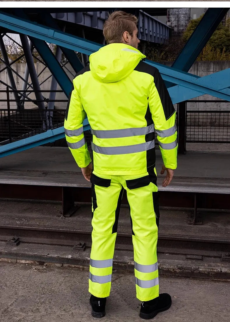 A man from the back wearing a high-visibility yellow and black waterproof jacket and trousers with reflective stripes.