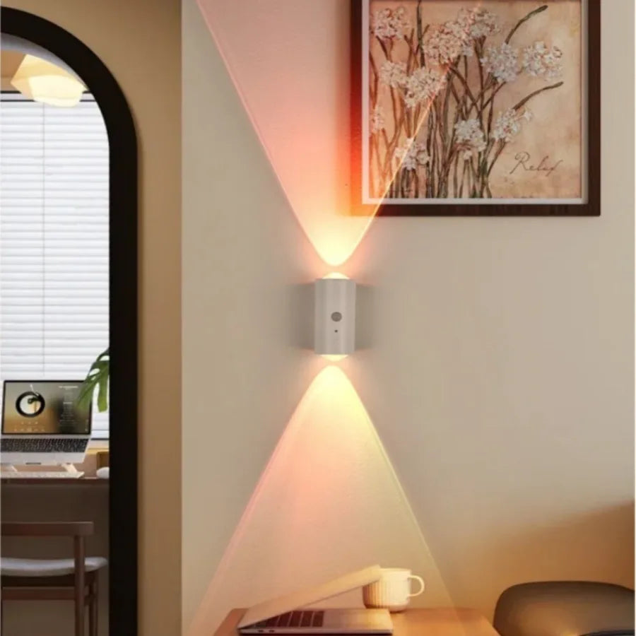 A modern white wall-mounted LED light with a motion sensor, casting elegant upward and downward beams of warm RGB light.