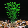 Bright green plastic aquarium plant with small leaves, set in a textured tan base on colorful gravel against black.