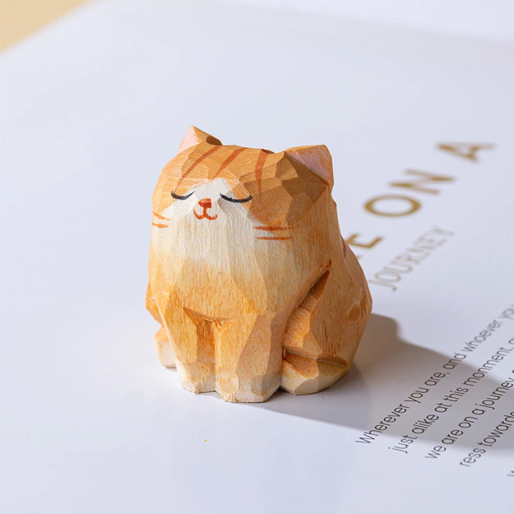 Small, hand-carved orange tabby cat figurine with a peaceful, sleeping expression and faceted wooden texture.
