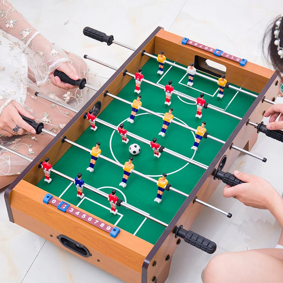 Tabletop foosball game with a wooden-effect frame, green pitch, colourful plastic players, and manual score counters.