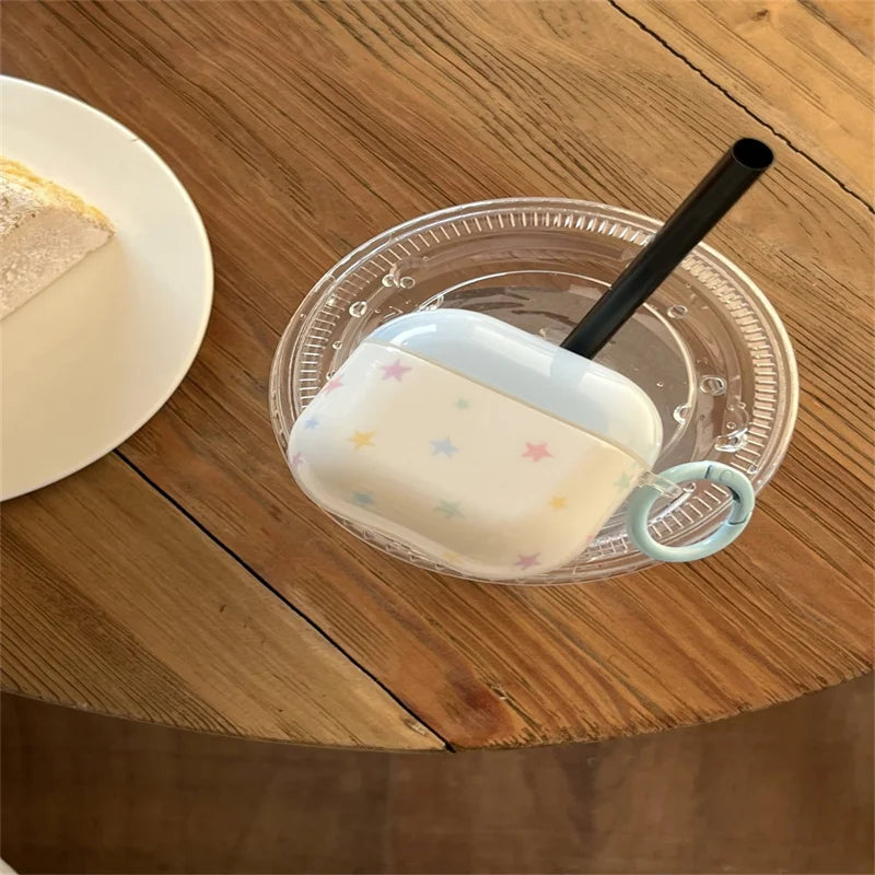 White AirPods Pro case featuring pastel-coloured star print, made from protective silicone with a blue ring hook.