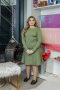 A woman wearing a sage green long-sleeved, ribbed knit top and a matching A-line skirt.