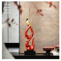 Tall, flame-shaped resin ornament with a shiny red and gold gradient finish, set on a sturdy black rectangular base.