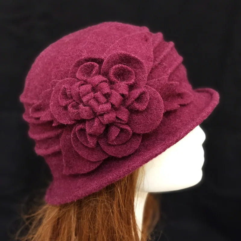 Elegant burgundy wool winter cloche hat with a decorative felt floral detail, modelled on a mannequin head.