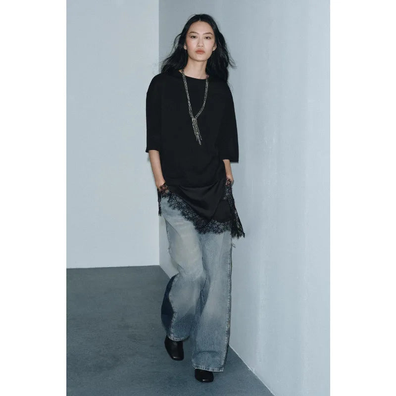 Black short-sleeve top with elegant side lace trim, paired with light-wash wide-leg denim jeans and a long necklace.