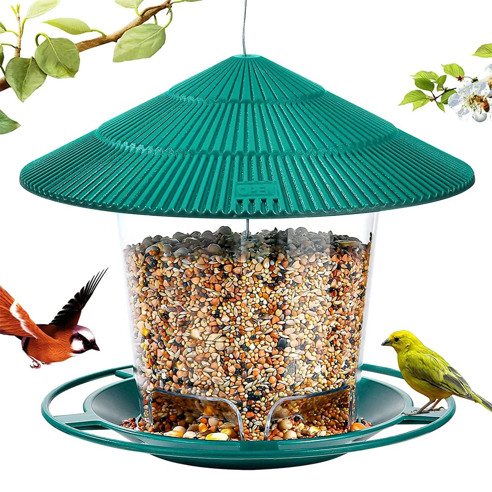 Green hanging bird feeder with a ridged roof, clear seed reservoir, and circular perch, surrounded by wild birds.