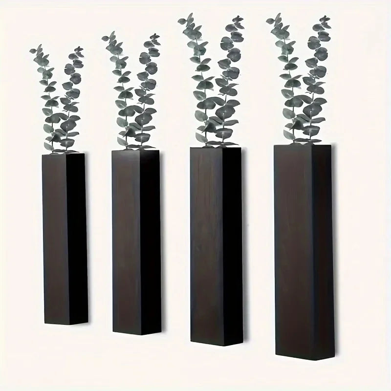 Four sleek, dark wood wall-mounted vases, each holding a sprig of eucalyptus against a plain white background.