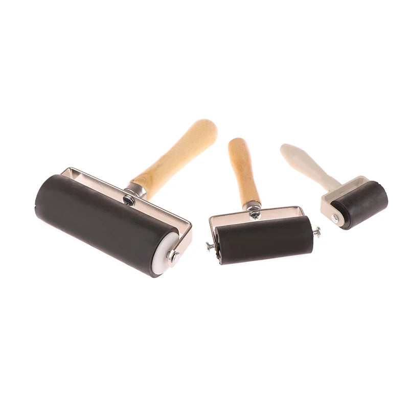 Set of three black rubber brayer rollers with wooden handles, ideal for printmaking, crafts, and ink application.
