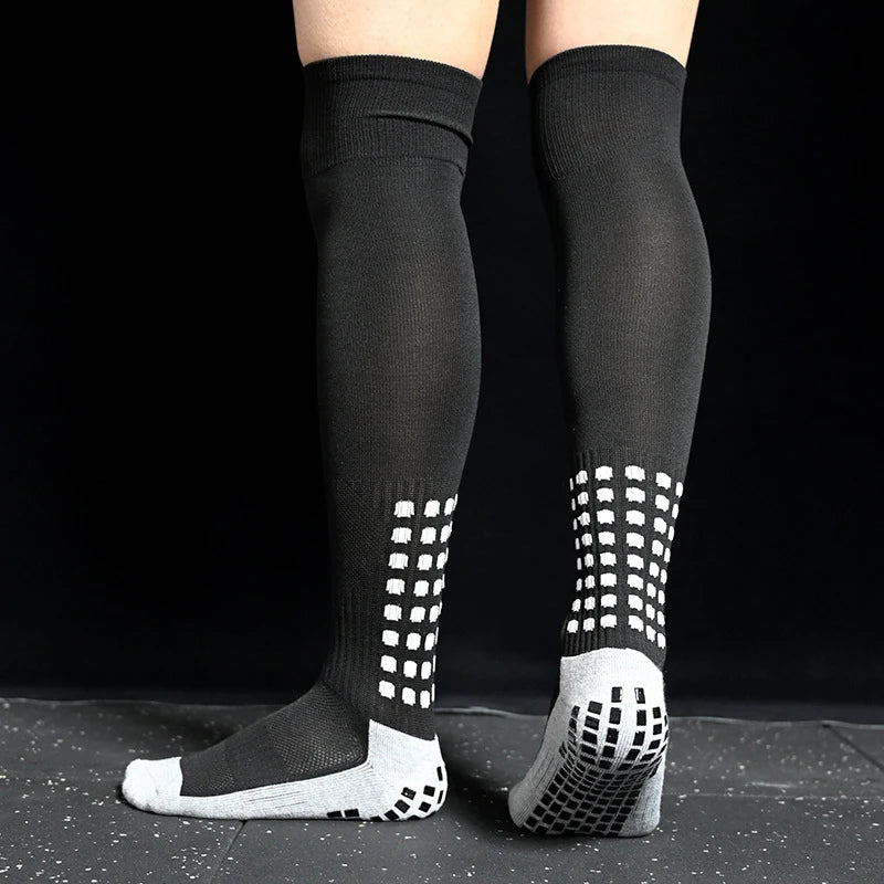 Black over-the-knee sports socks with white grip pattern on the feet and ankles for improved traction.