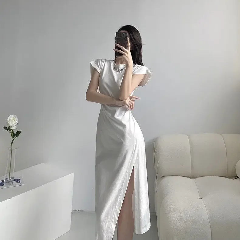 Woman wearing a sleek white midi dress with cap sleeves and a high side slit, styled in a minimalist aesthetic.