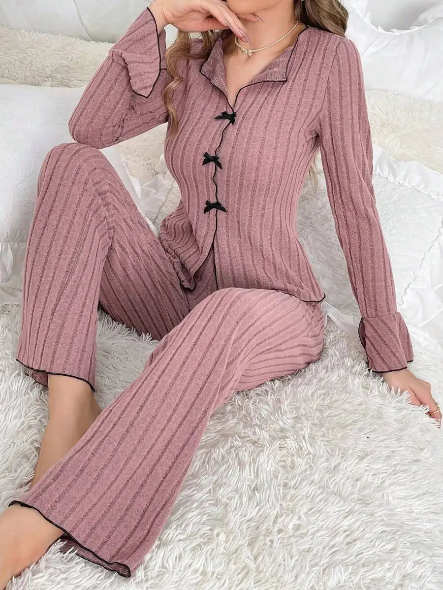 Dusty pink ribbed pyjama set with long sleeves, flared cuffs, and black ribbon bow detailing on the front.