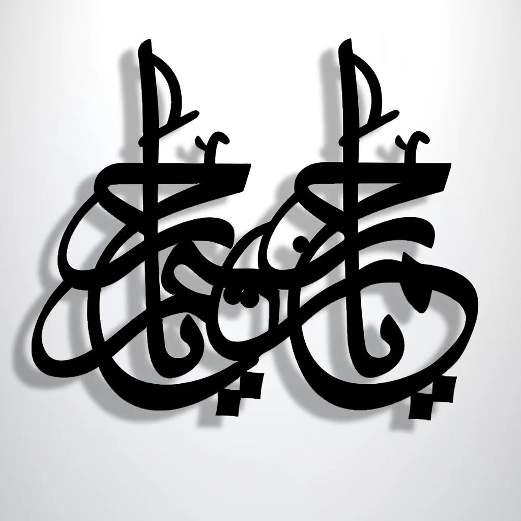 Black decorative wall art featuring two identical, intricate abstract Arabic-style calligraphic symbols.