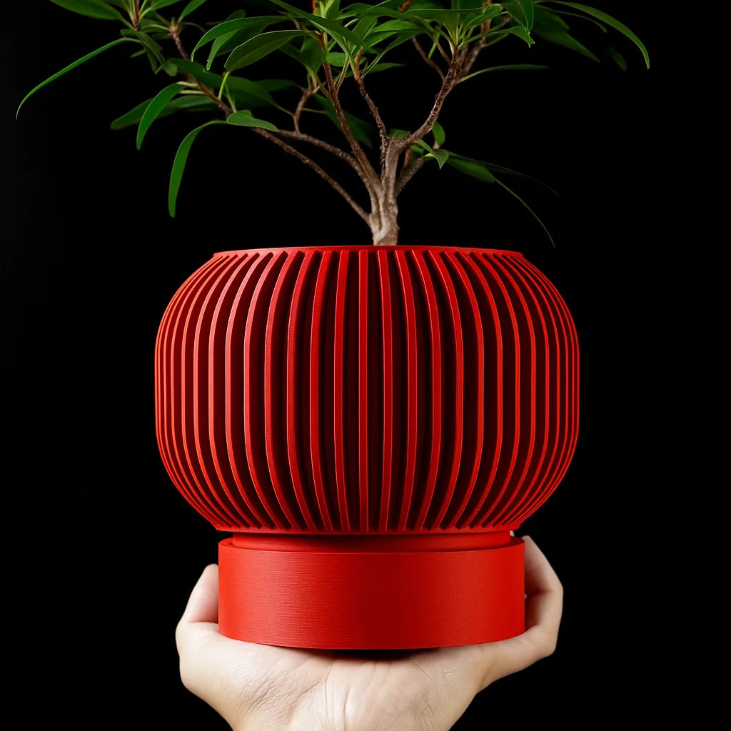 A hand holds a vibrant red, 3D-printed plant pot with vertical ridges and a smooth base, containing a green plant.