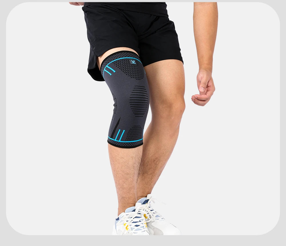 A person wearing a grey and black compression knee support sleeve featuring bright blue accents and a textured knit.