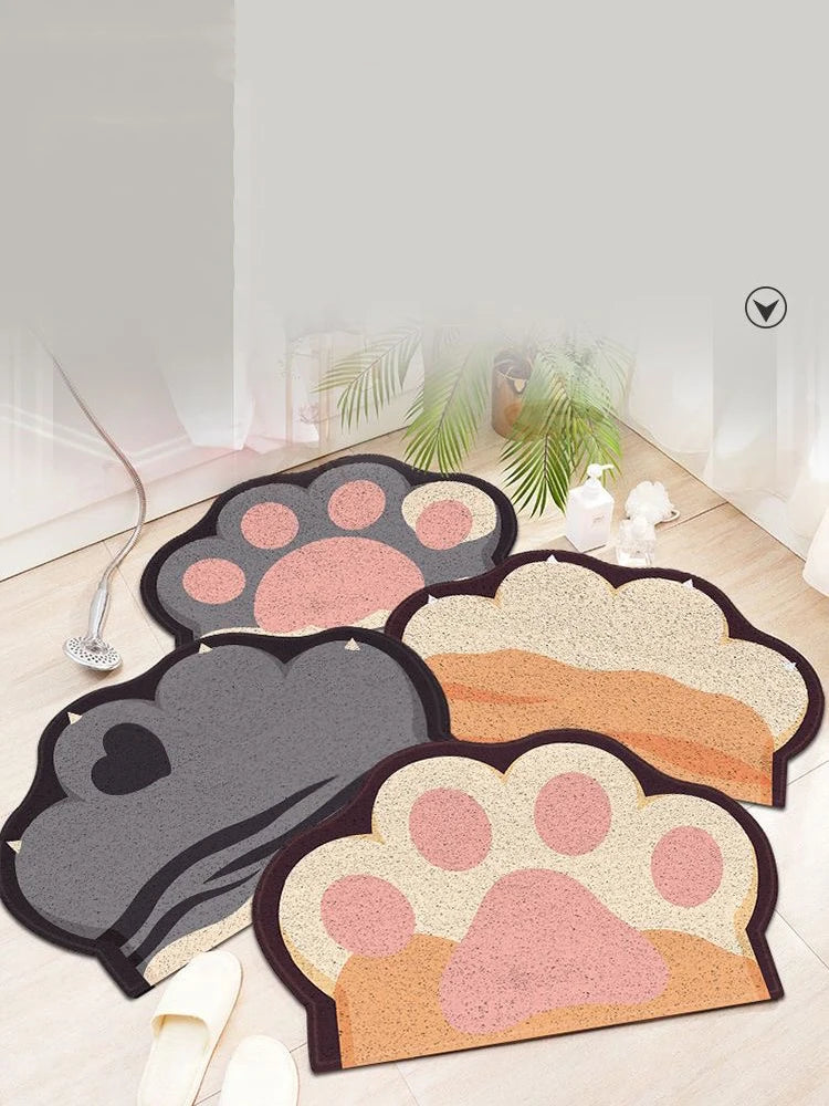 Four cat-paw shaped litter trapping mats in beige, pink, and grey, featuring textured surfaces and anti-slip backing.