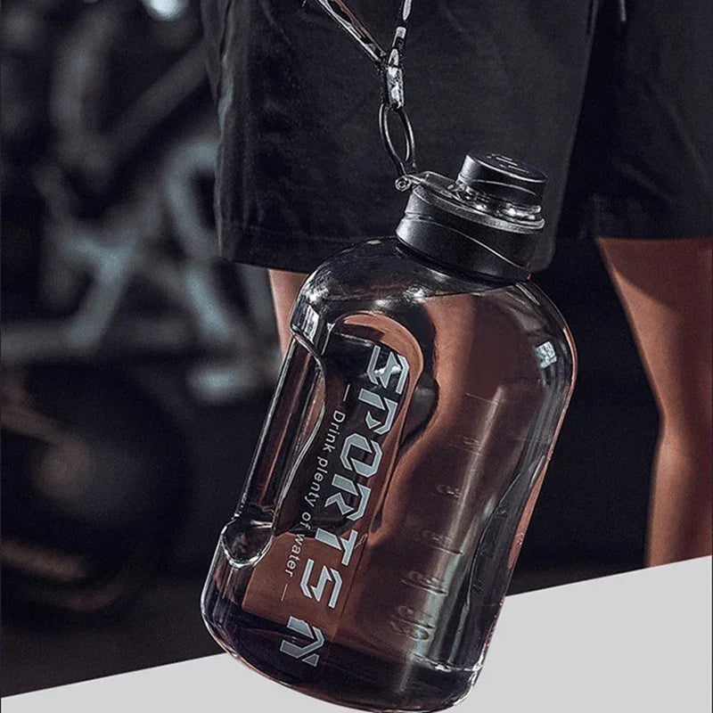 Large, clear black sports water bottle with a carry handle and black screw cap, held by a lanyard.