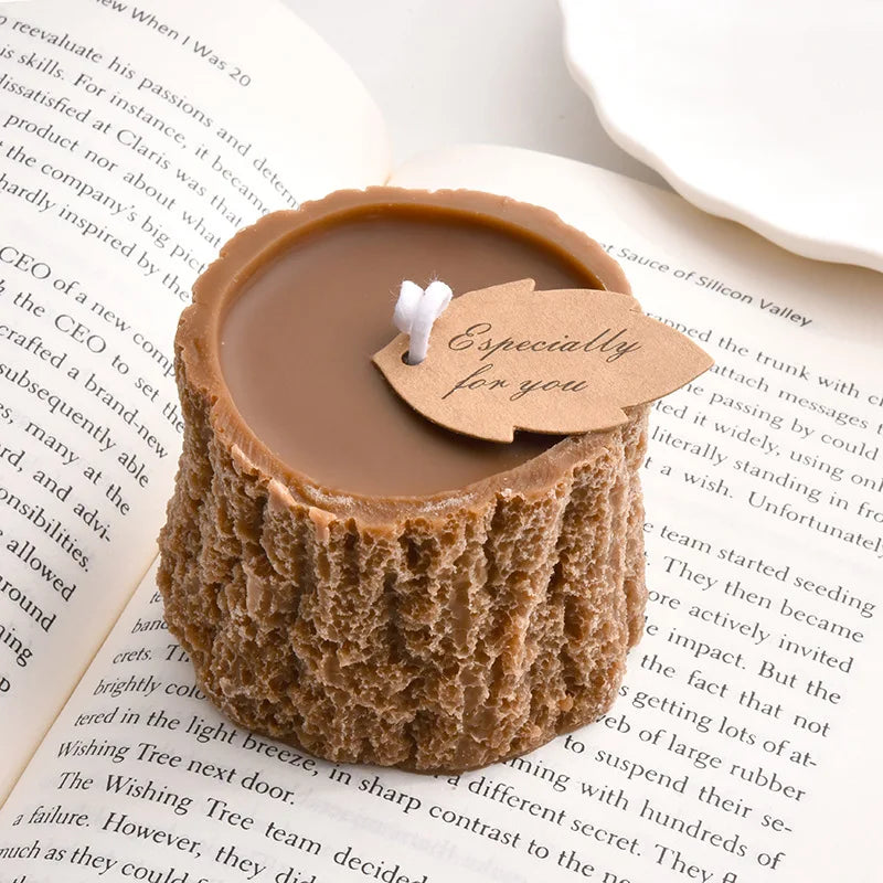 Brown wax candle shaped like a tree stump, with a white wick and a leaf-shaped tag reading "Especially for you."