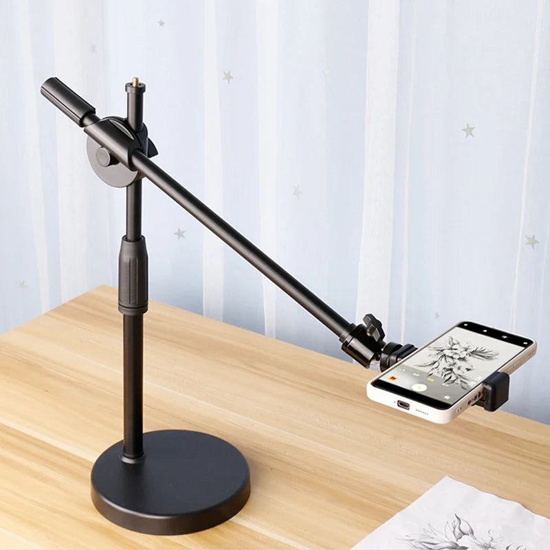 Black adjustable desktop phone stand with a long arm, stable circular base, and rotatable smartphone holder clip.