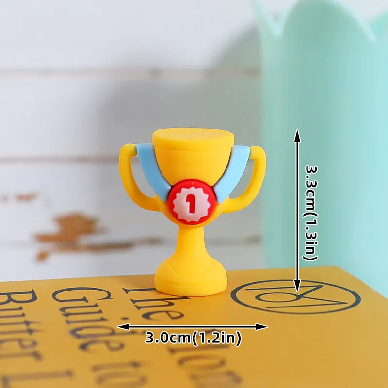 Small yellow trophy-shaped eraser with light blue accents and a red number one badge. Measures 3.3cm x 3cm.