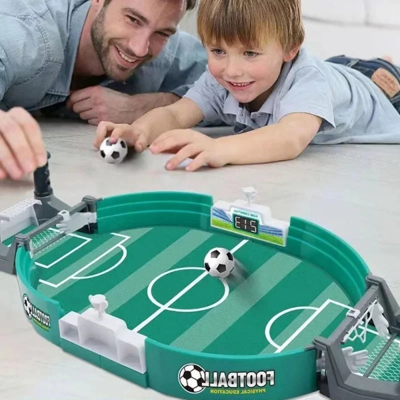 A child and adult playing with a green tabletop football game featuring a digital score tracker and two mini balls.