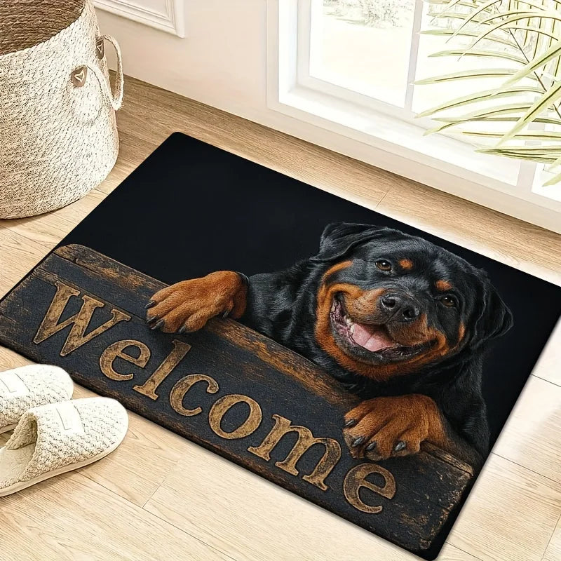 Black rectangular doormat featuring a smiling Rottweiler leaning over a rustic 'Welcome' sign. Soft fleece texture.