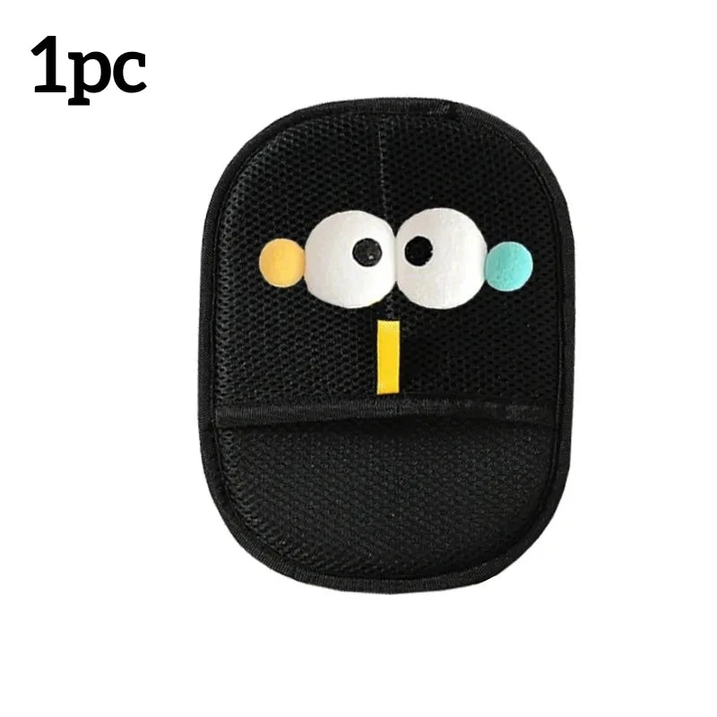 Black mesh exfoliating mitt featuring a cartoon face with big white eyes and small yellow and blue accents.