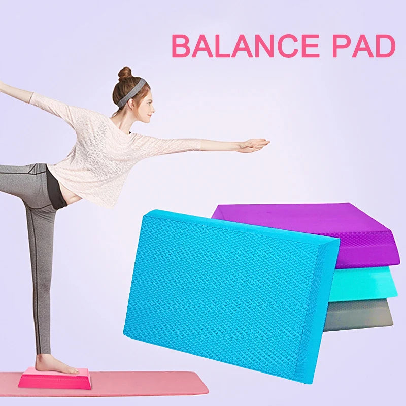 A woman balancing on a pink foam pad. Stacked blue, purple, teal and grey TPE foam balance pads with textured surfaces.