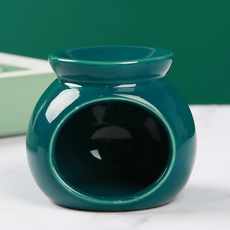 Glossy, dark green ceramic oil burner with a rounded, modern design and top wax melting bowl.