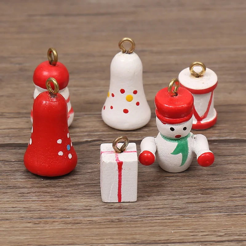 Assorted small, hand-painted wooden Christmas tree ornaments featuring festive figures, bells, and gift shapes.
