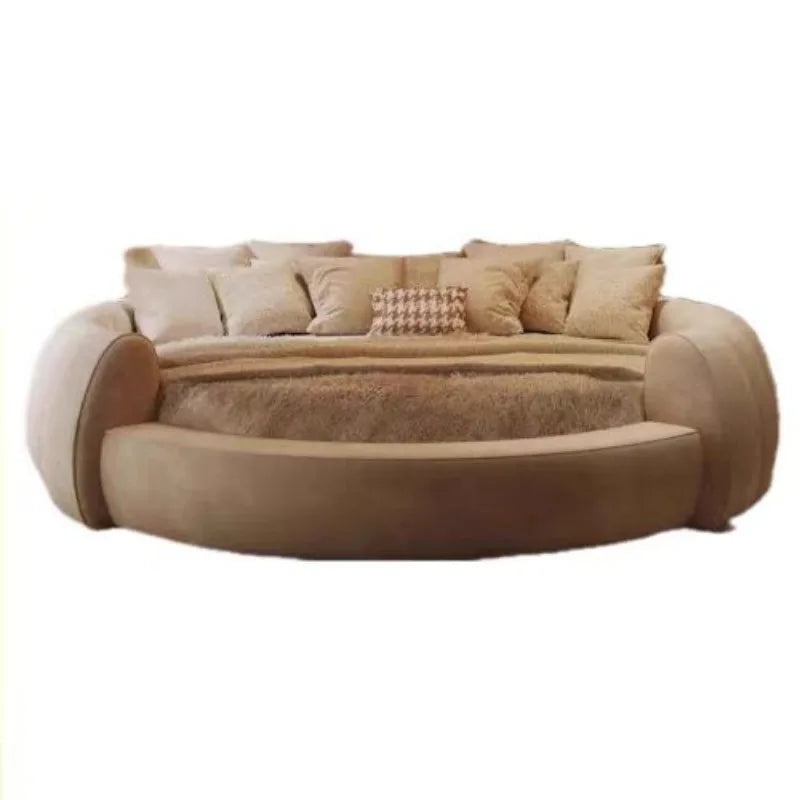 A modern, circular beige upholstered bed featuring a plush, curved frame and multiple decorative scatter cushions.