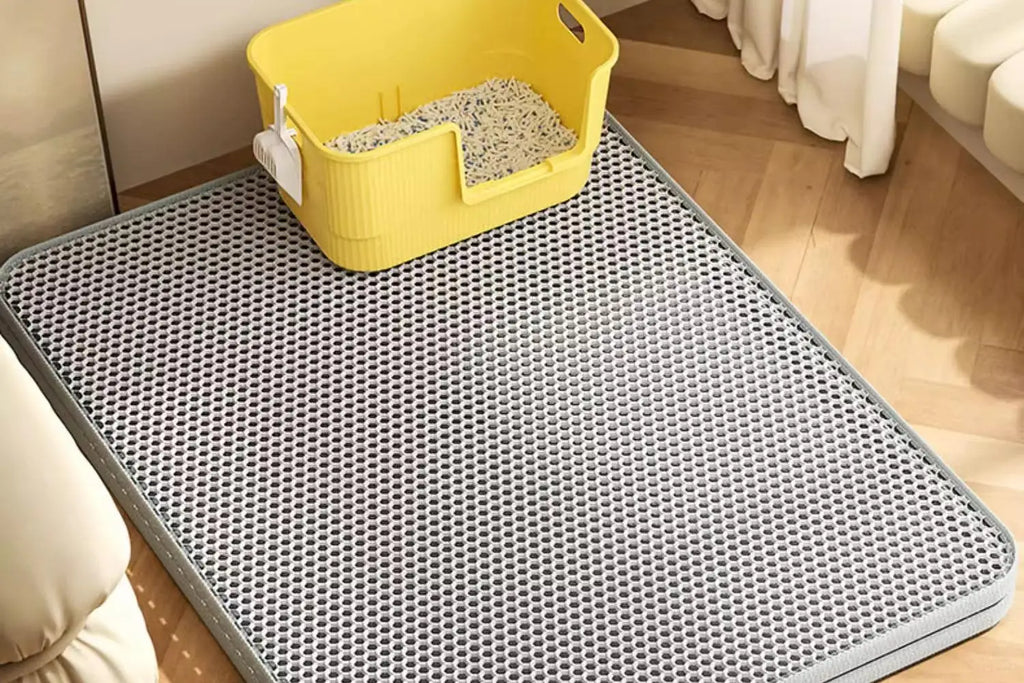 Grey honeycomb-textured waterproof cat litter mat on a wooden floor, with a yellow litter tray placed on top.