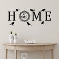 Black self-adhesive wall sticker spelling 'HOME', with an 'O' shaped as a floral wreath and silhouettes of birds.